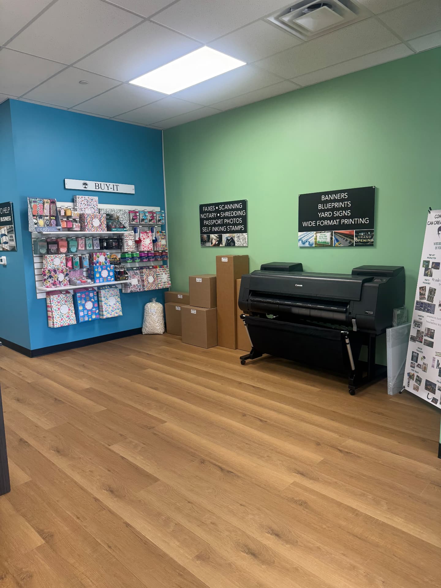 Wide format printer next to the notary, passport photo and scanning signs at The Connection Tree Ship and Print in Freehold, New Jersey